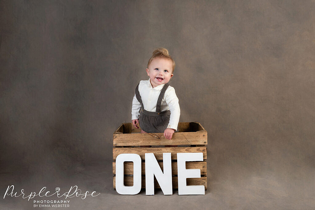 Child standing in front of a sign sayinf one