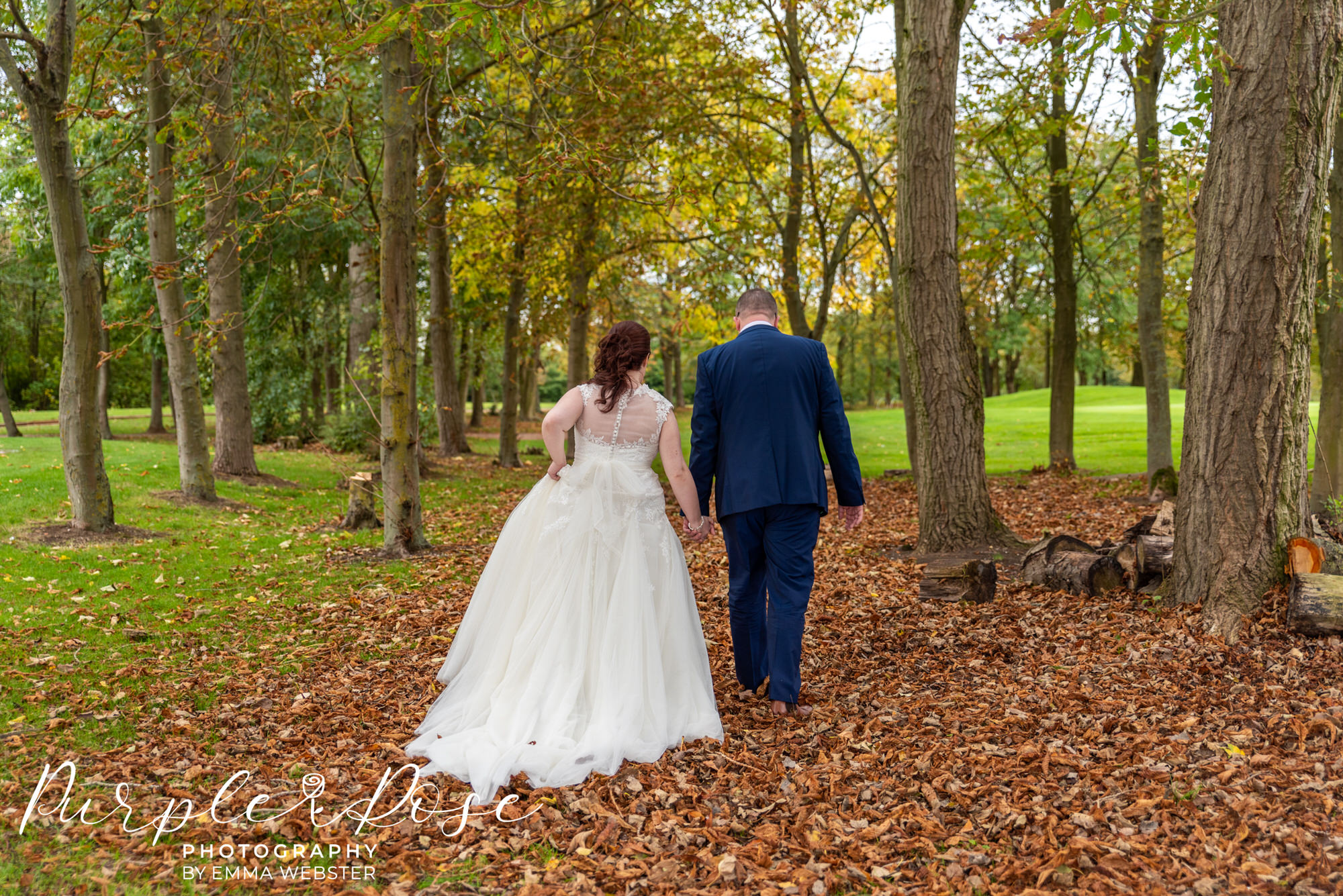 Bride and groom walking through autumn leafs