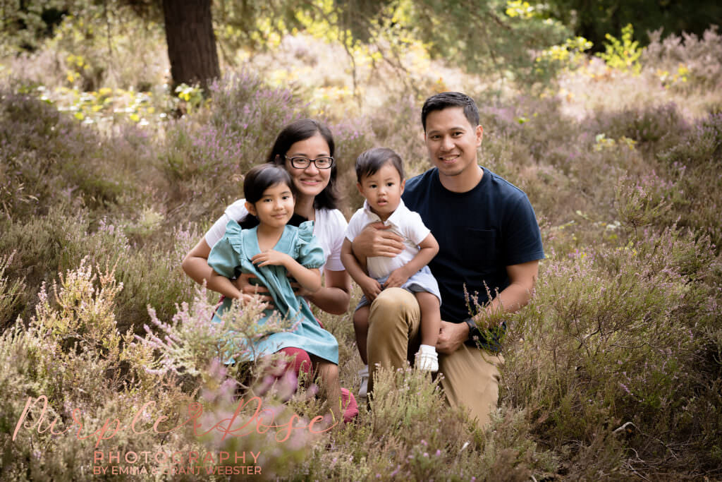Family smiling in a wooded area