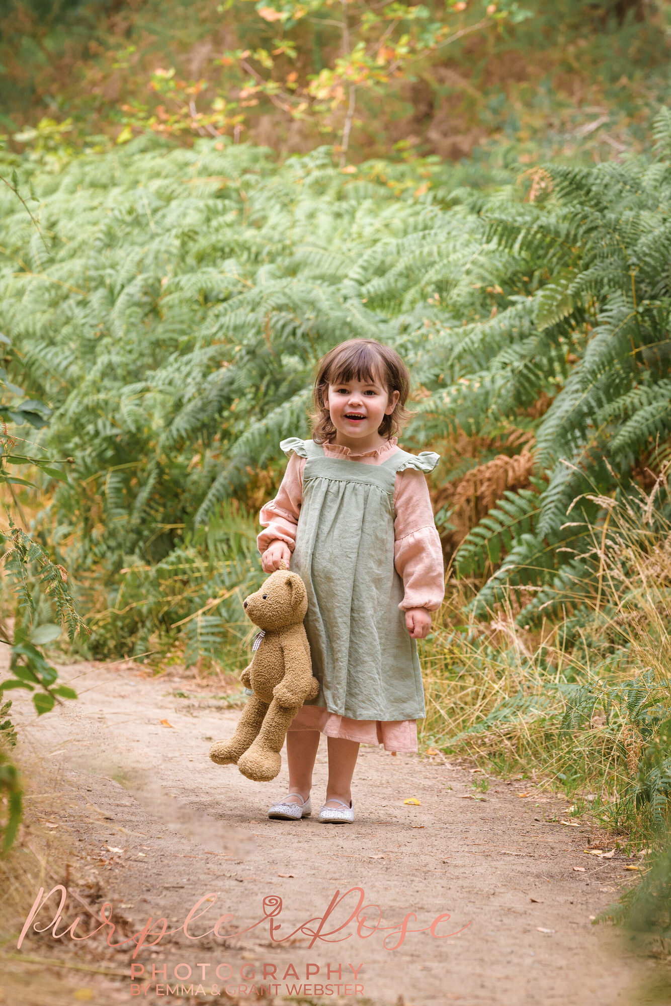 Little girl walking down a lane holding her teddy bear