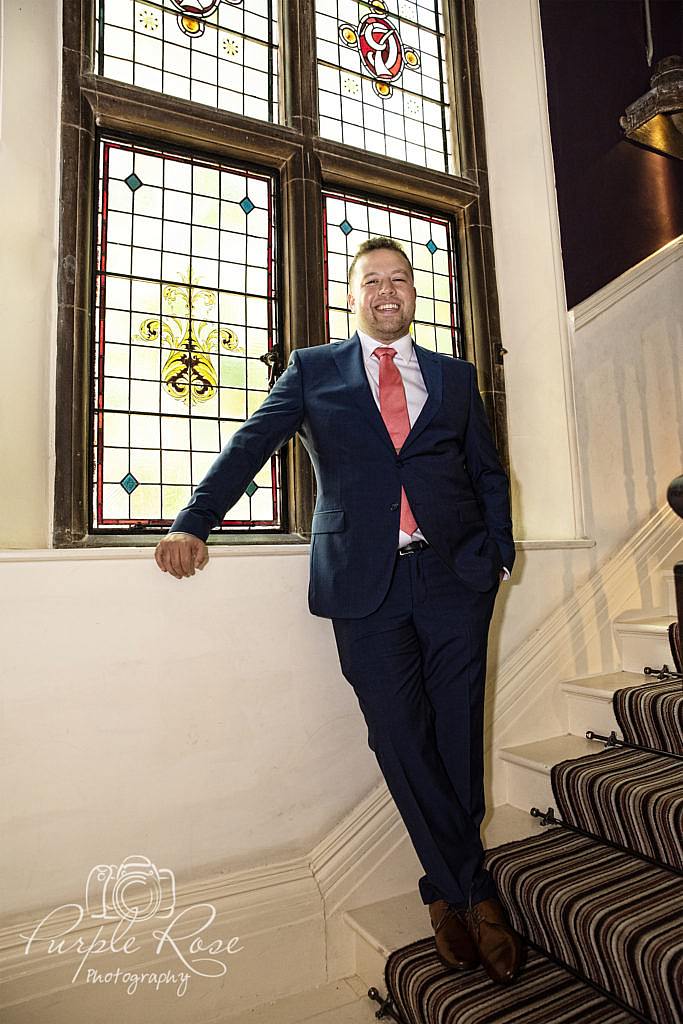 Groom leaning by a window