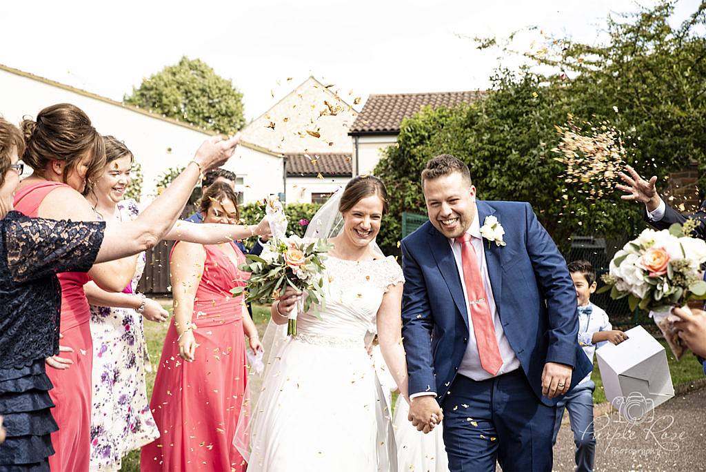 Bride and groom being showered with confetti