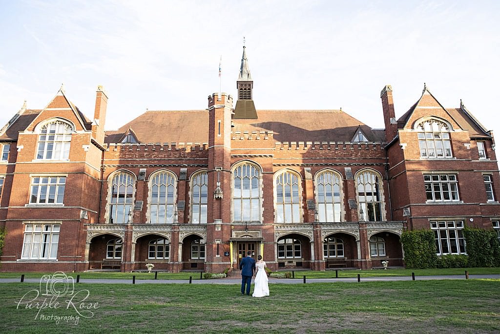 Bride & groom standing in front of their wedding venue Bedford School