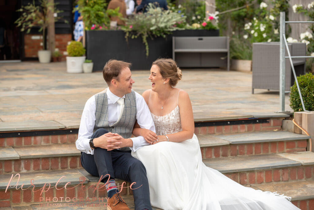 Photo of a bride and groom sat on steps at their wedding venue in Milton keynes