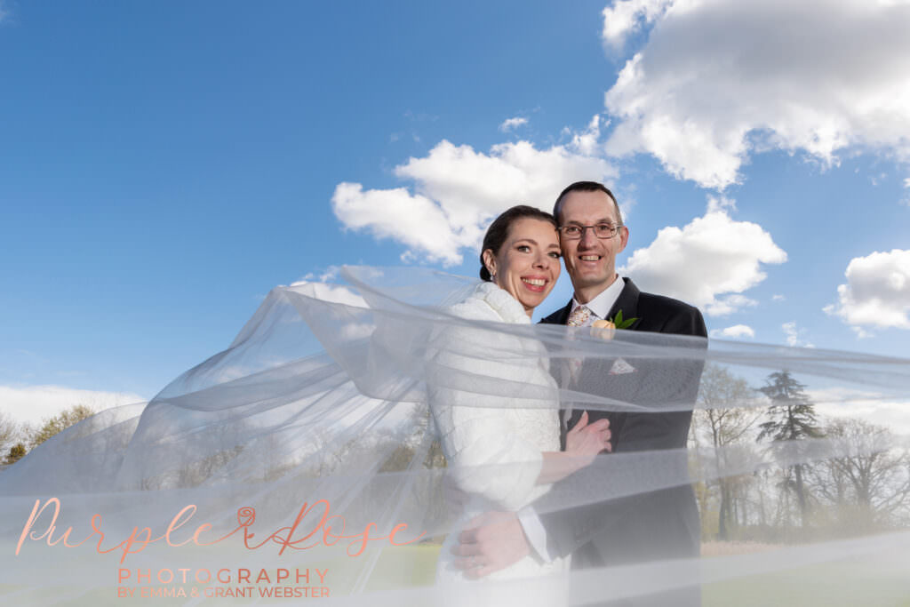 Photo of bride and groom on their wedding day in front of a blue sky in Milton Keynes