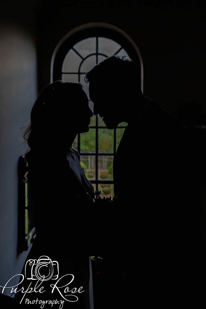Silhouette of bride and groom in front of a window