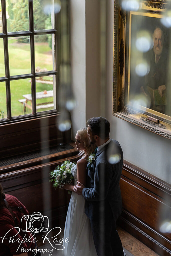 bride and groom standing by a window