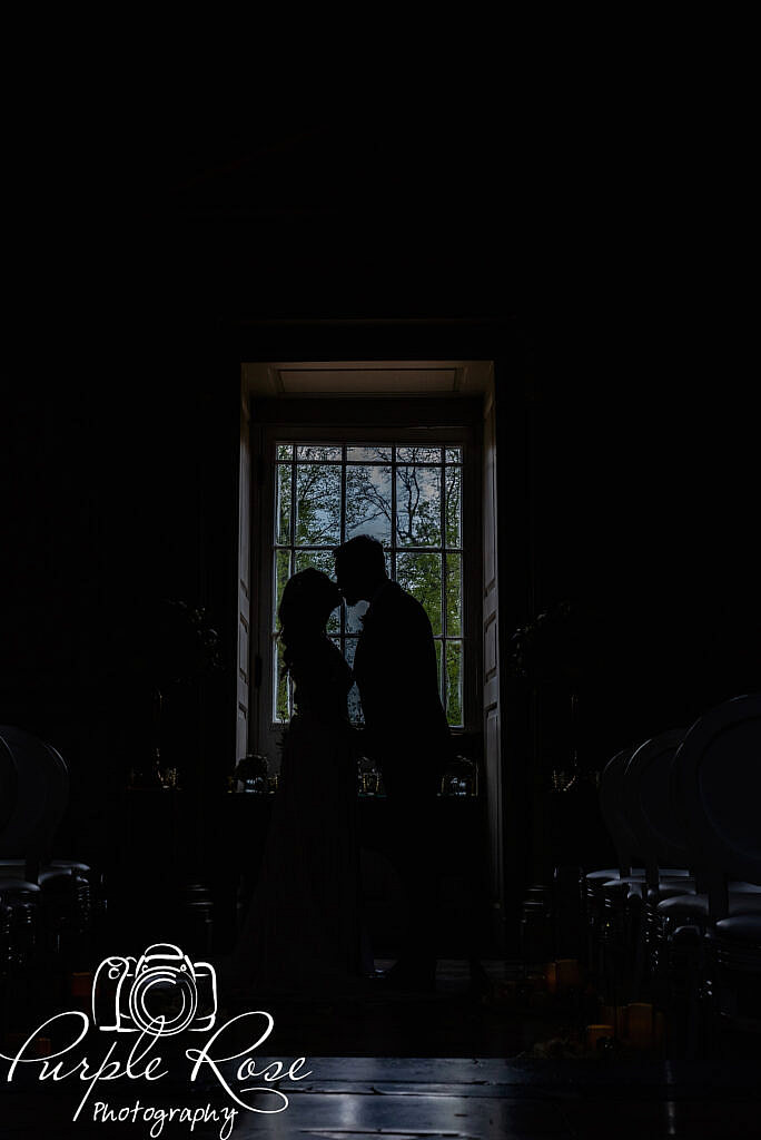 Silhouette of bride and groom in front of a large window