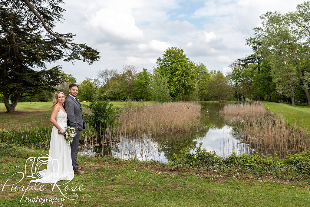 Bride and groom standing by a lake