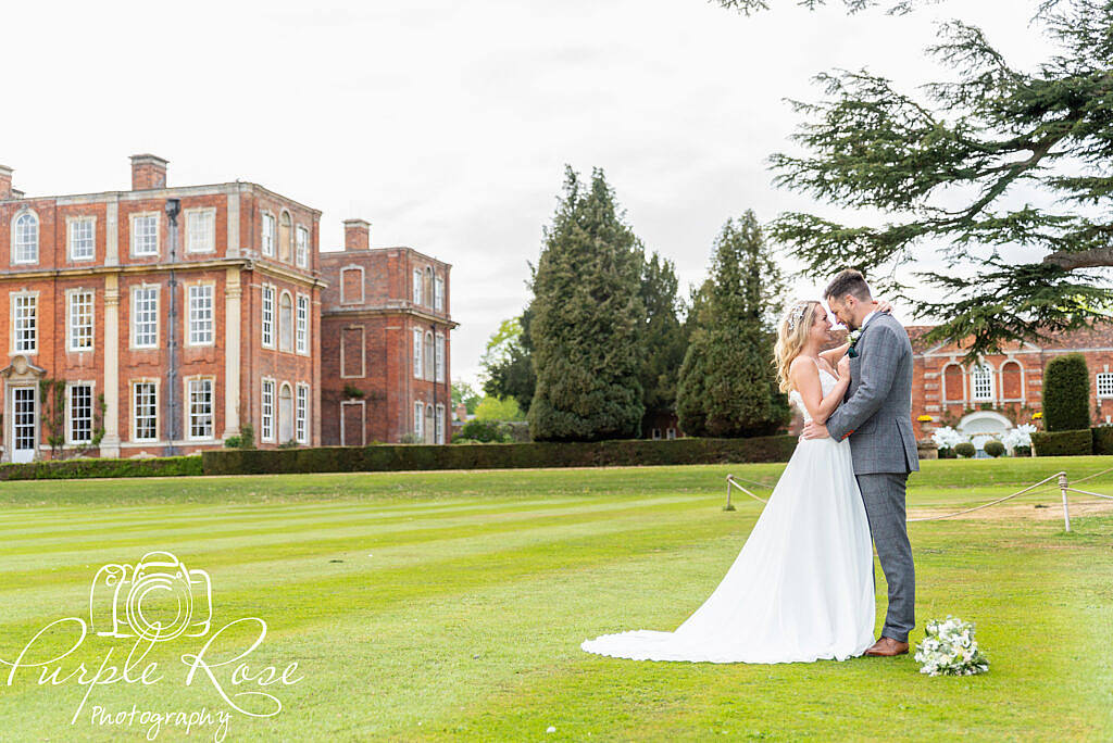 Bride and groom embracing in their wedding venues gardens