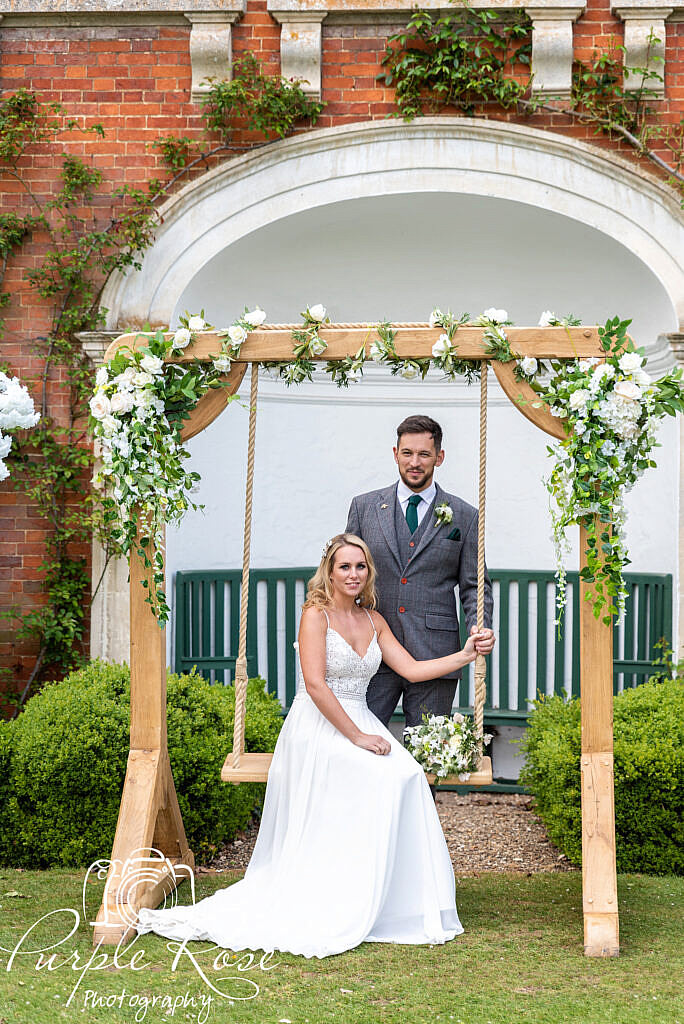 Bride and groom on a swing in their wedding venues garden
