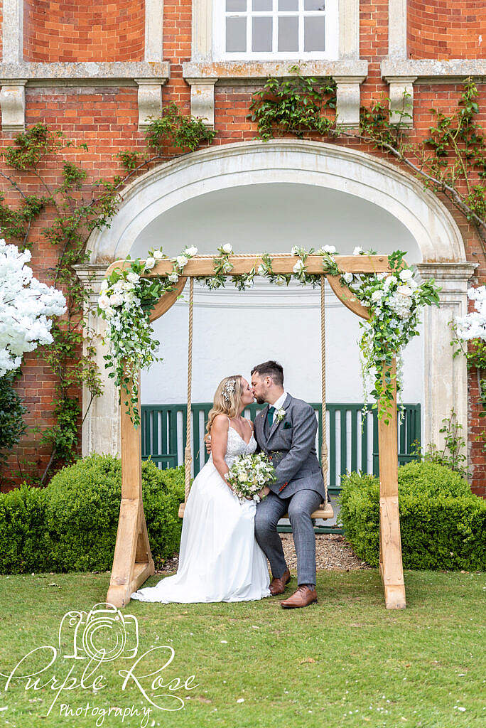 Bride and groom kissing on a swing