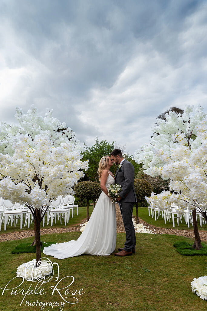 Bride and groom standing in wedding venues garden with a dramatic sky