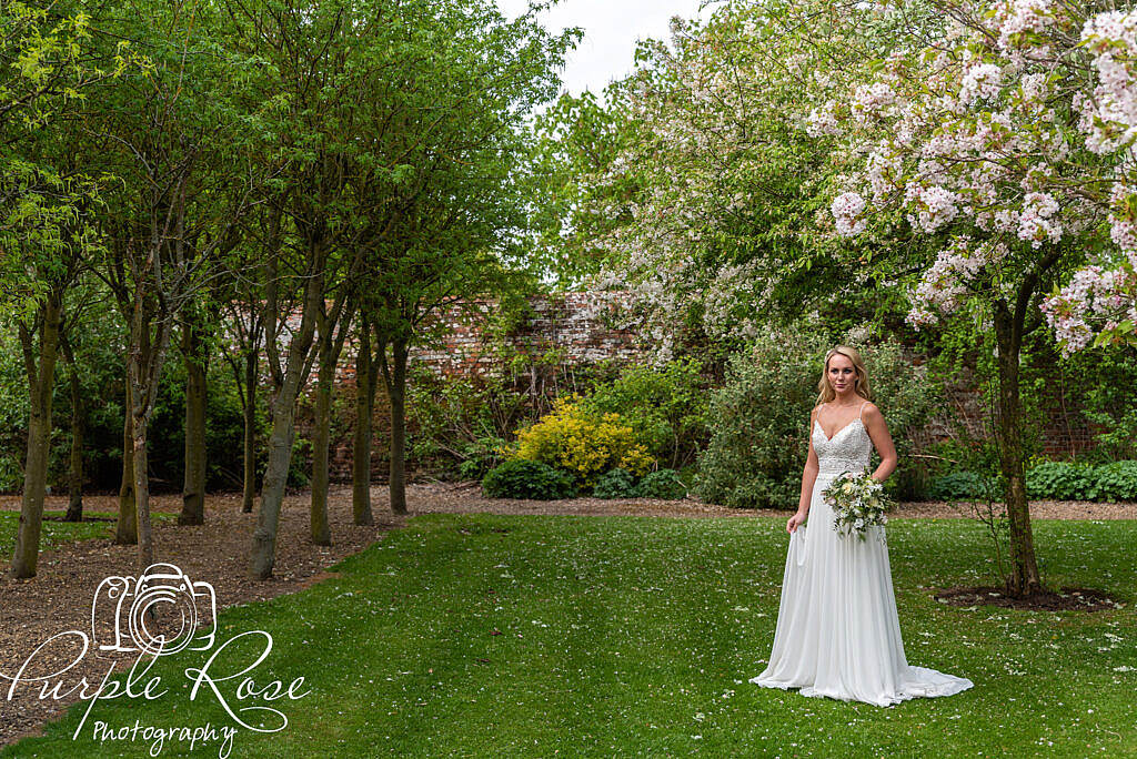 Bride standing among cherry blossom