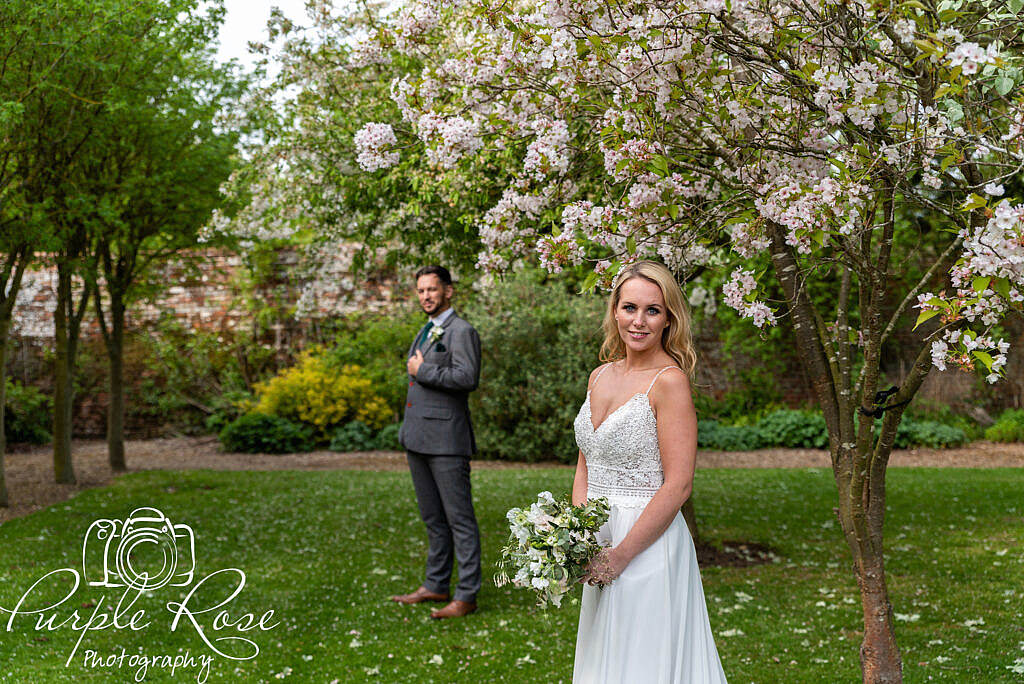 Bride smiling while her groom stand s in the background