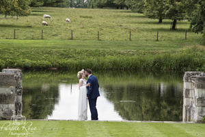 Bride and groom standing in front of a lake