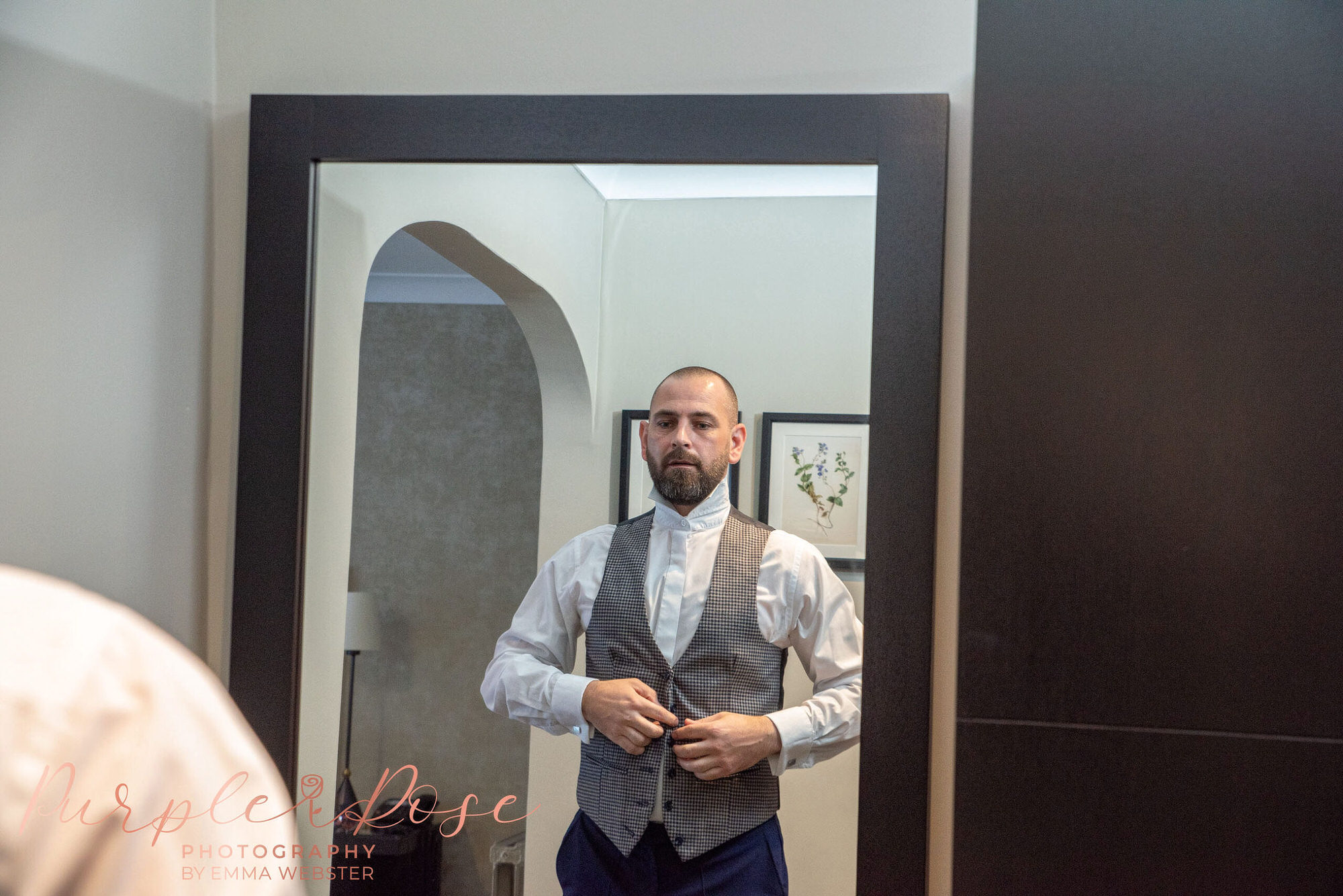 Groom buttoning up his waist coat