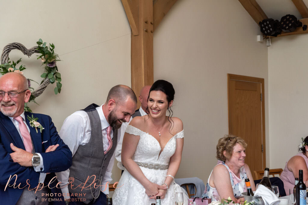 Bride and groom laughing during wedding speeches