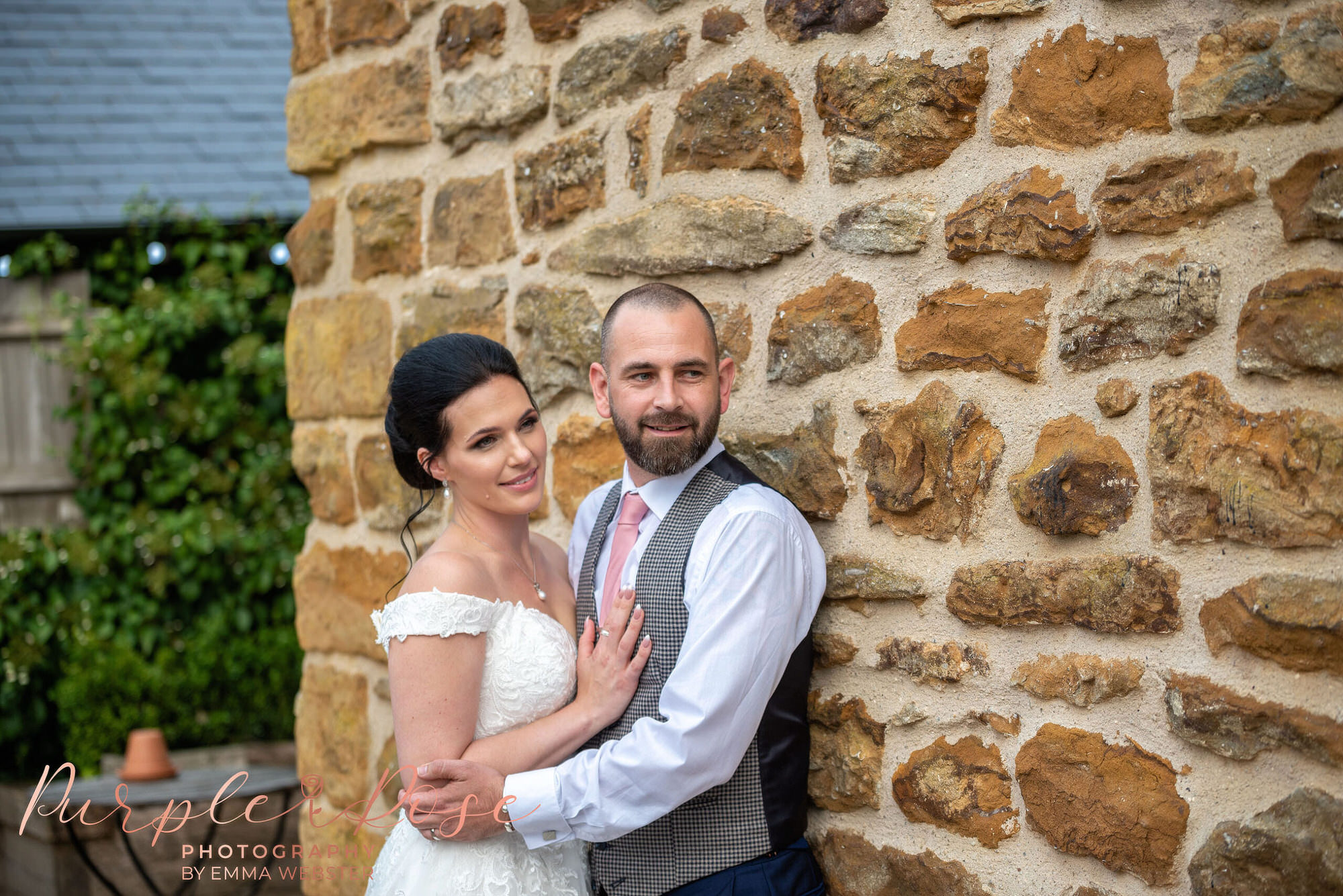 Bride and groom leaning on a wall