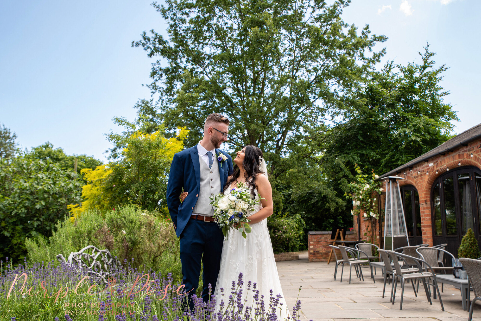 Bride and groom looking into each others eyes, stood behind lavender