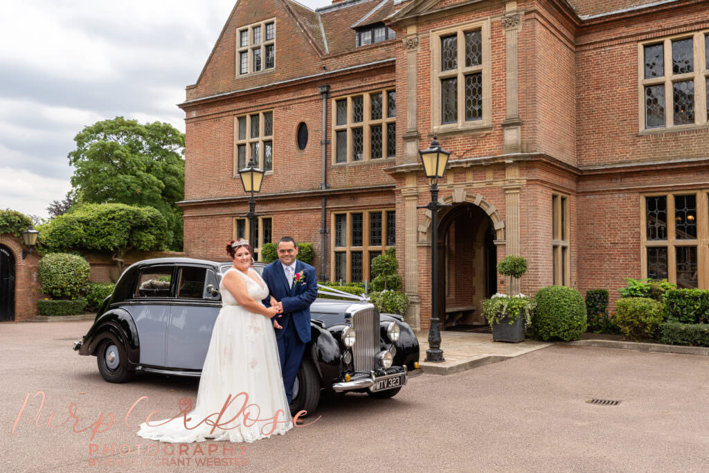bride and groom stood by theier wedding car outside wedding venue in Milton Keynes