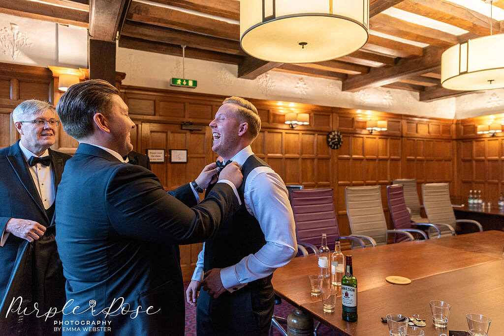 Best man adjusting the grooms bow tie