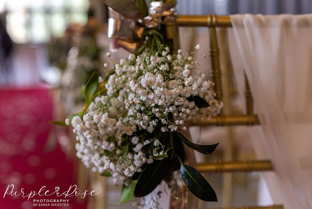 Flowers tied to chair in wedding ceremony room