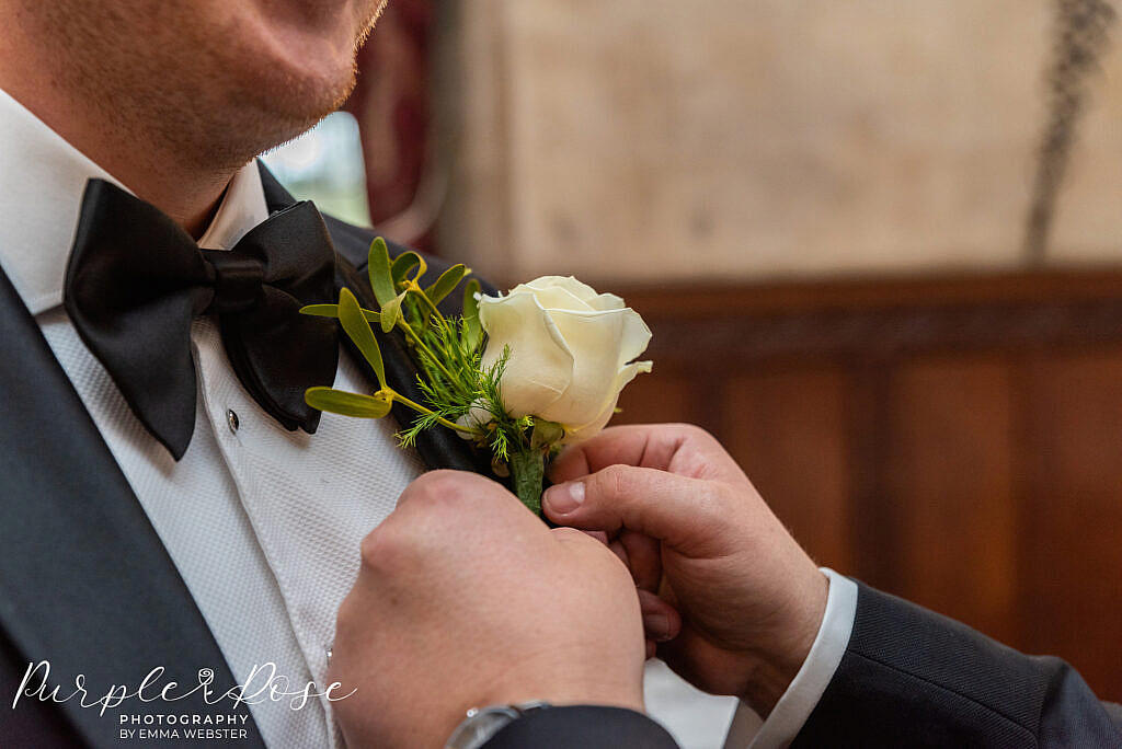 Grooms button hole being attached