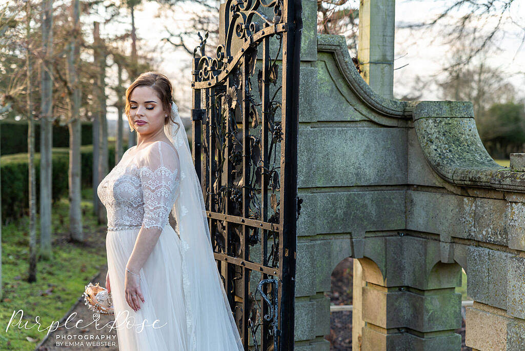 bride standing by a metal gate