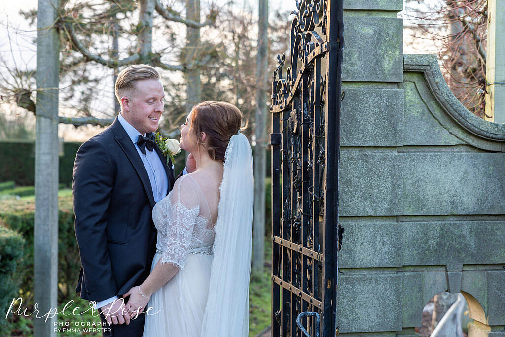 bride and groom standing by a metal gate