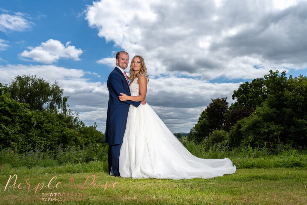 Bride and groom in front of a bright sunny sky on their wedding day in Milton Keynes