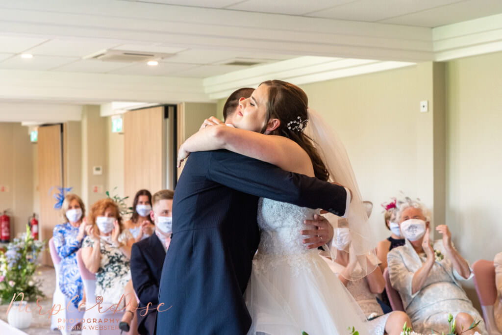 Bride and groom lembracing during their wedding ceremony