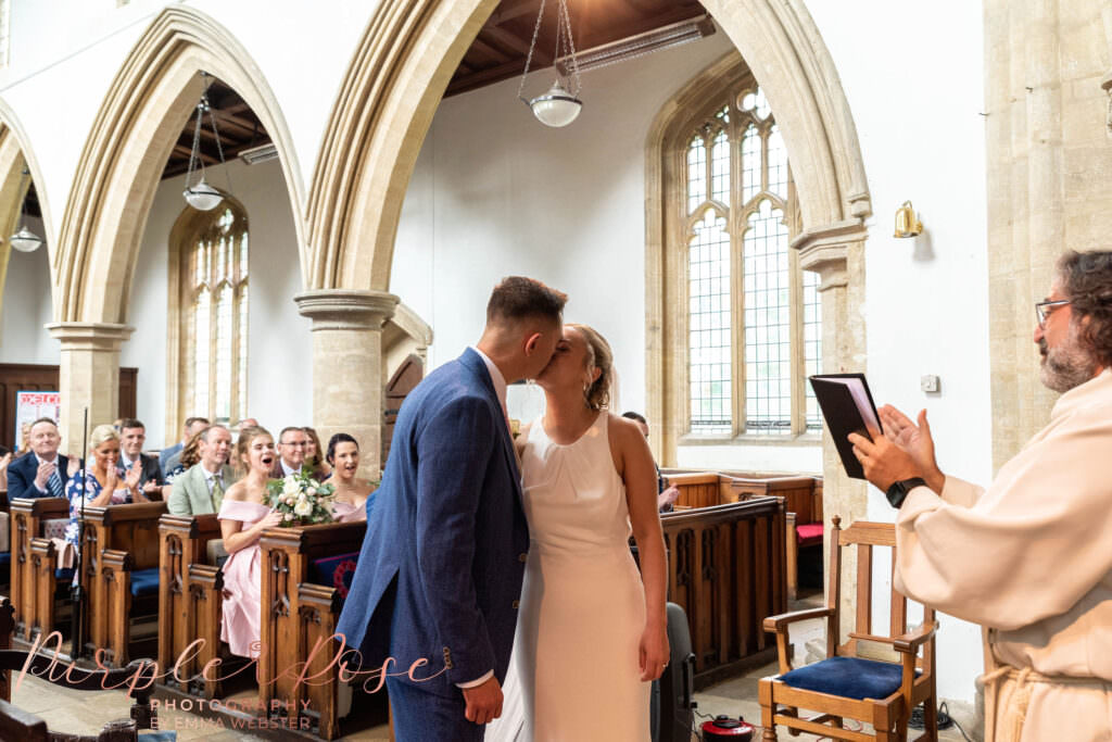 Bride and groom kissing in church at the end of their wedding ceremony