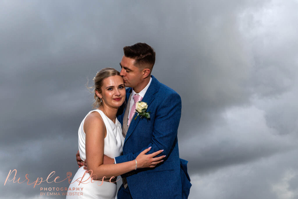 Groom kissing his bride on the forehead