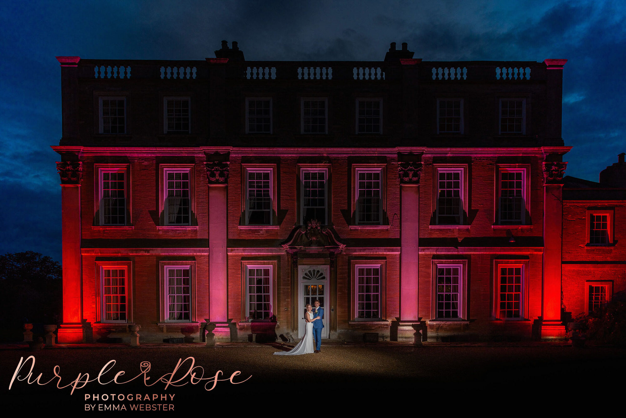 Night-time phot of bride and groom in front of their wedding venue