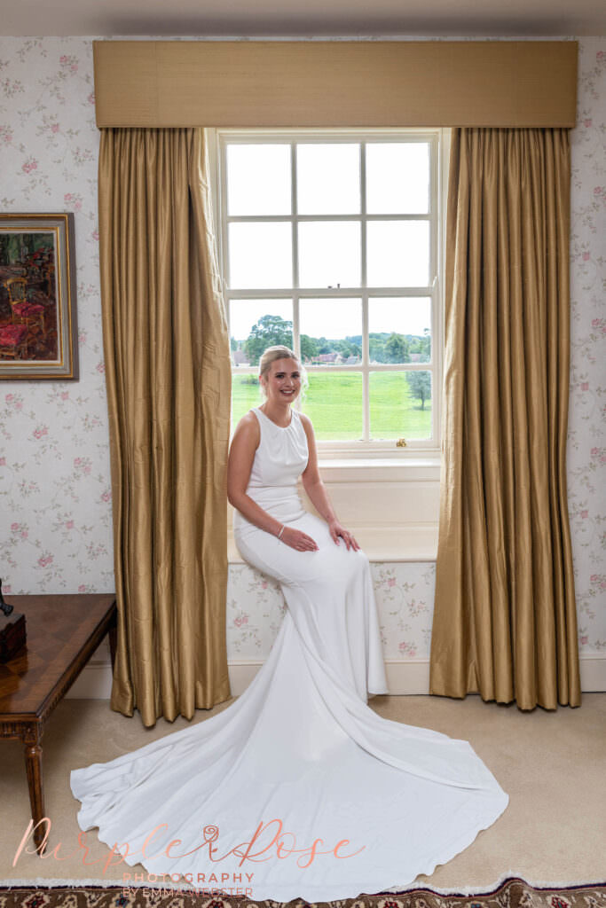 Bride sat in wedding dress on a bay window