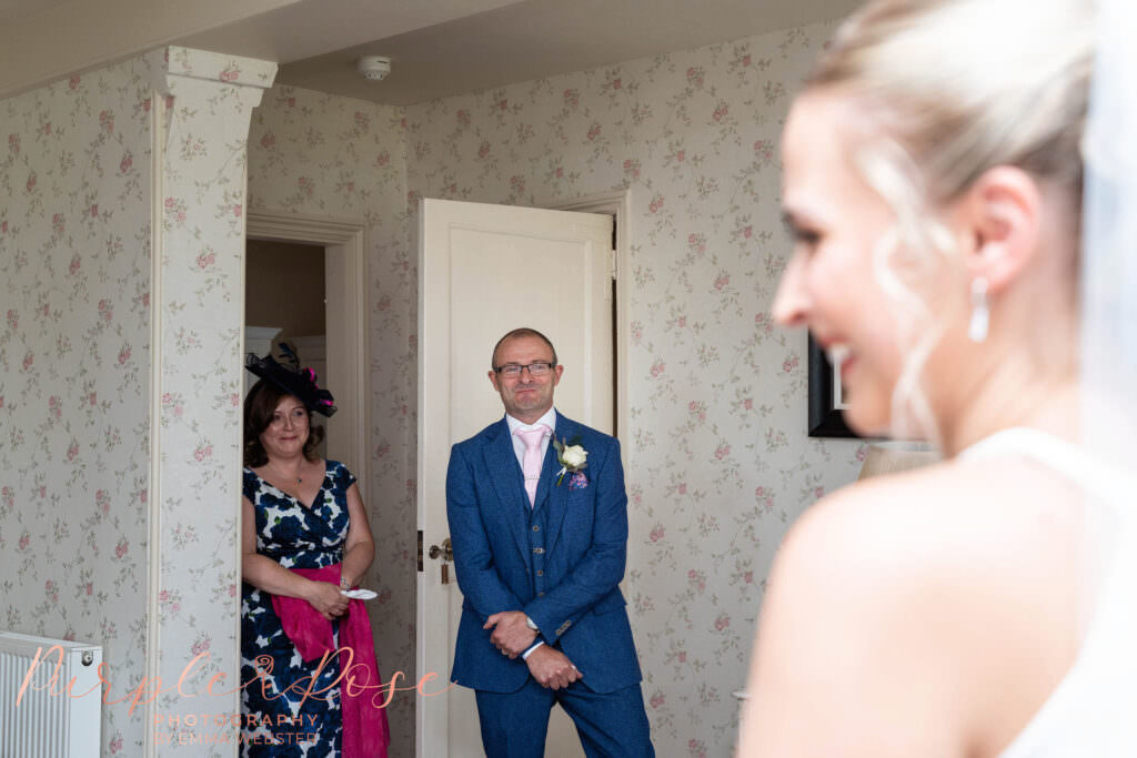 Mother and father seeing their daughter in her wedding dress for the first time