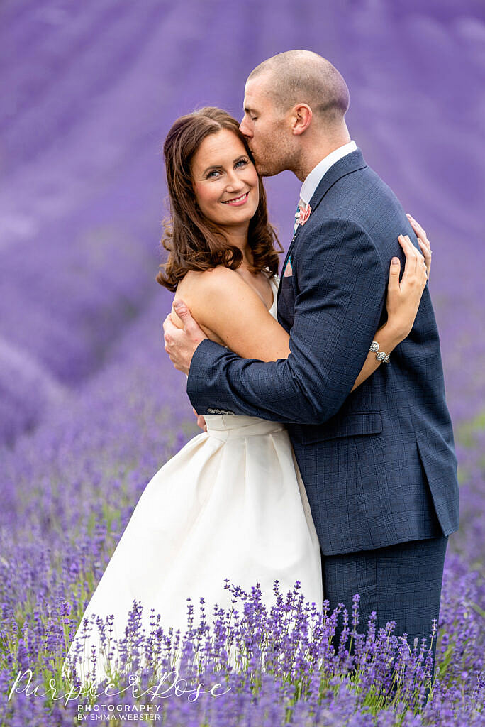 Bride being kissed by her groom in a lavender field