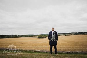 Groom standing in front of open fields