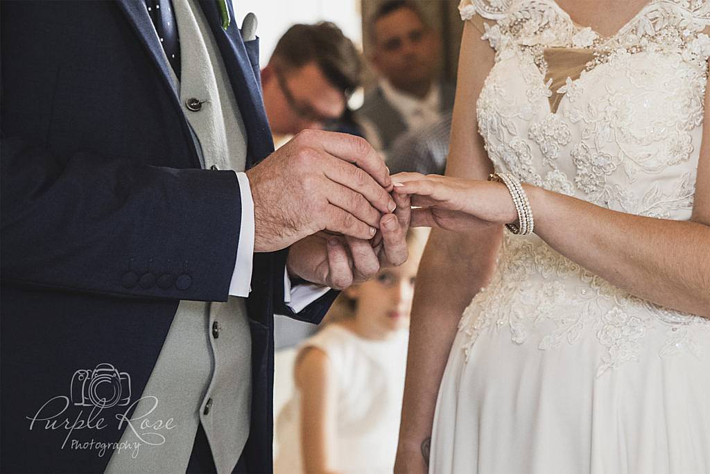Groom placing wedding ring on brides finger