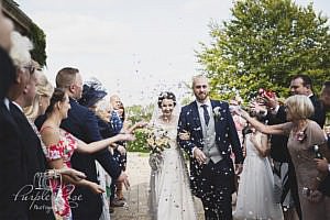 Bride and groom having confetti thrown at them