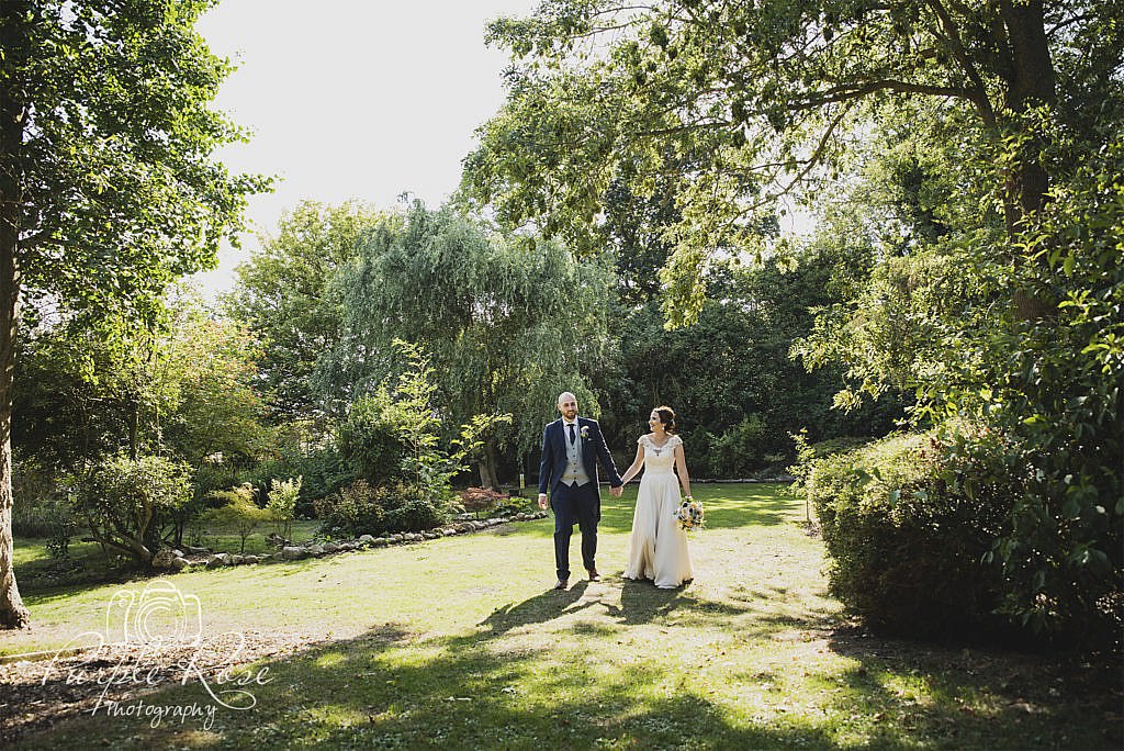 Bride and groom walking through gardens