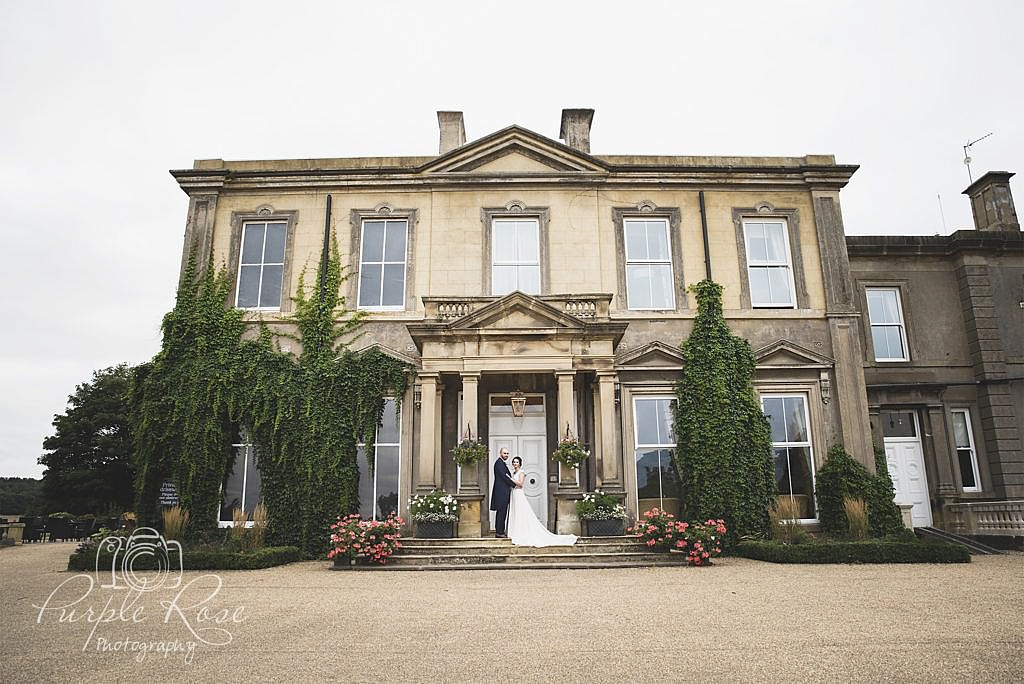 Bride and groom stood on steps of their wedding venue