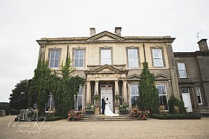 Bride and groom embracing in front of their wedding venue