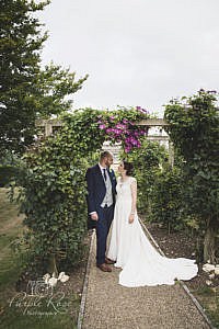 Bride and groom stood under a floral arch