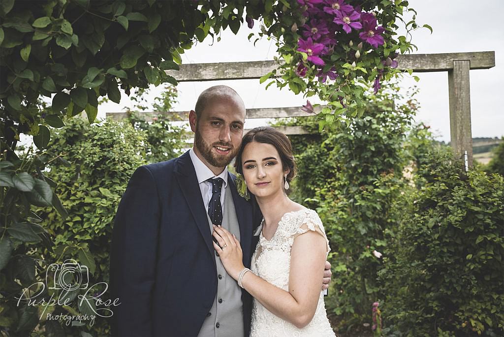 Bride and groom in a flower covered archway