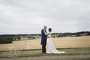 Bride and groom standing in front of an open field