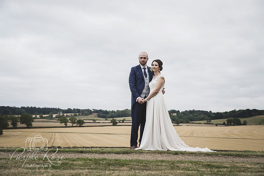 Bride and groom with open fields behind them