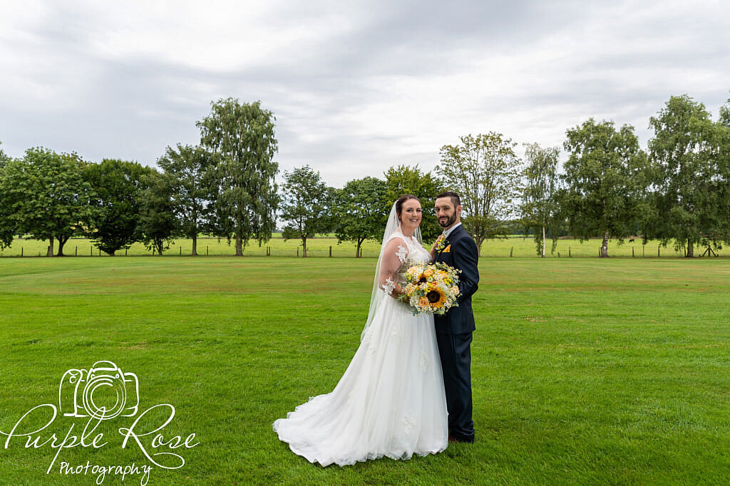 bride and groom standing by a golf course