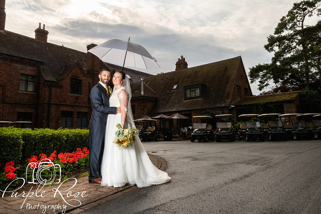 Bride and groom sheltering under an umbrella